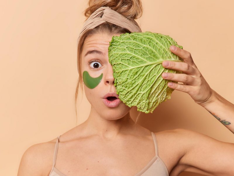 Amazed Surprised Woman Holds Breath Feels Amazed Holds Fresh Cabbage Face Applies Hydrogel Patches Eyes Remove Wrinkles Undergoes Beauty Procedures Isolated Beige Background