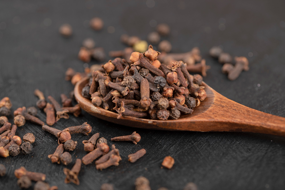 pile-dried-natural-cloves-with-wooden-spoon-black-surface