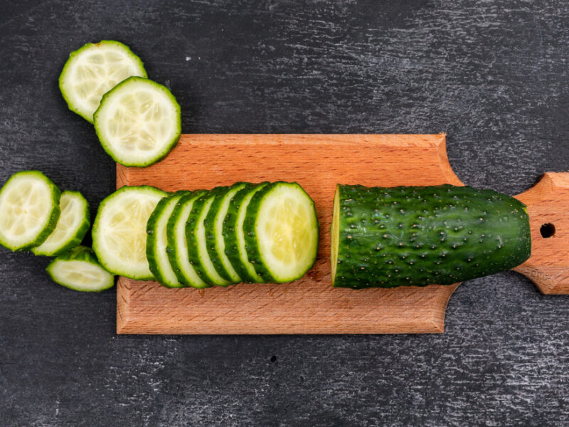 Top View Cucumber Sliced Wooden Cutting Board Black Stone Horizontal