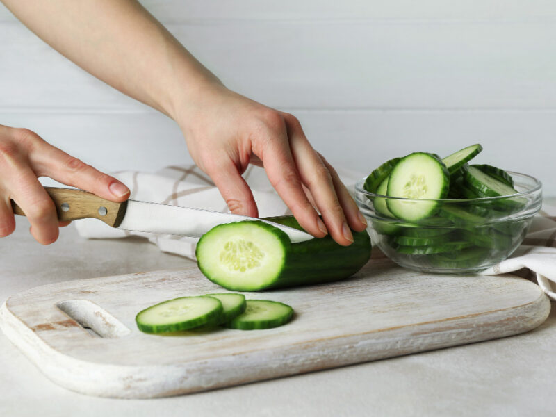 Woman Cuts Cucumber Wooden Board