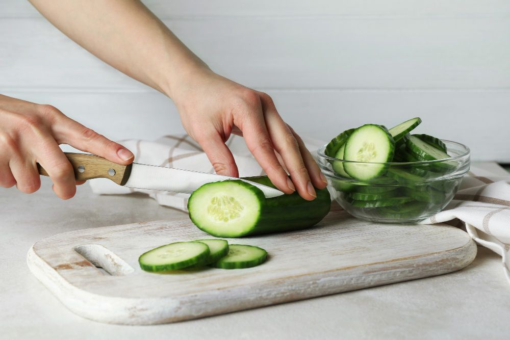Woman Cuts Cucumber Wooden Board