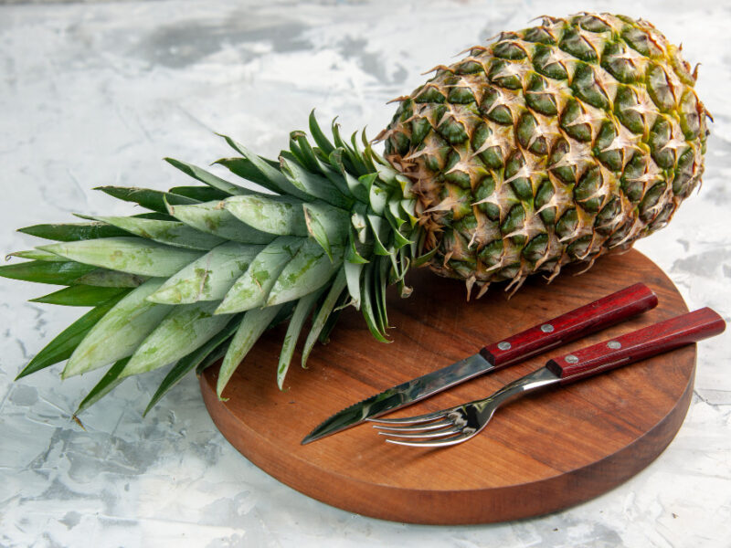 Front View Whole Fresh Golden Pineapple Fork Knife Cutting Board Marble Surface