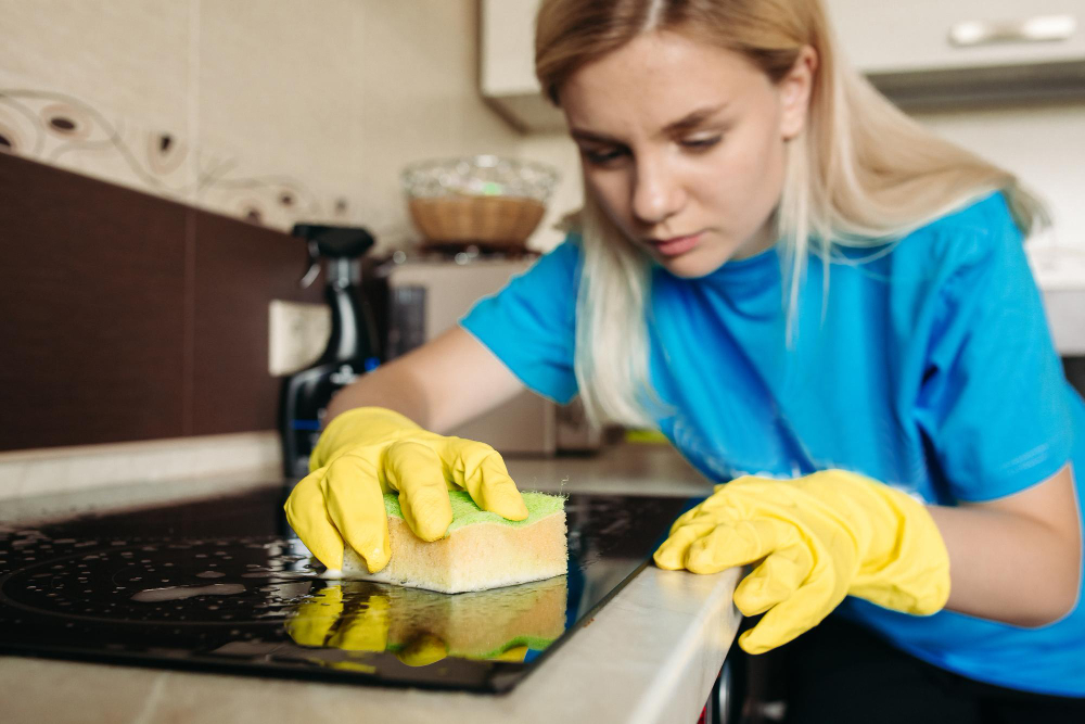 Close Up Woman Wearing Protective Glove With Rag Cleaning Electric Stove Home Kitchen Beautiful Girl Washing Black Shiny Surface Kitchen Top Hand With Foam Sponge Housework Concept