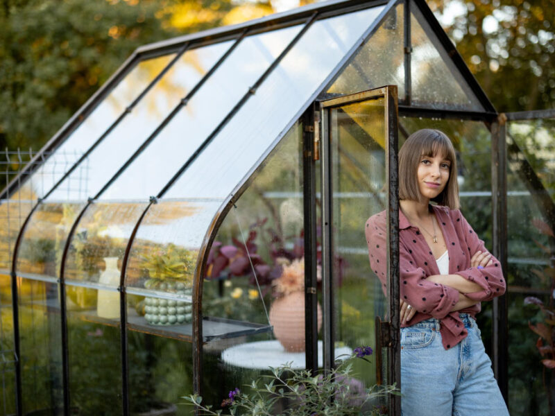 Woman Near Greenhouse With Flowers Back Yard