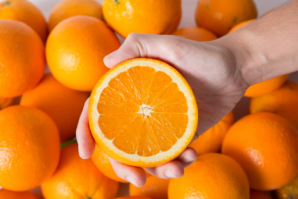 Person Showing Cut Orange Half Pile Fruits