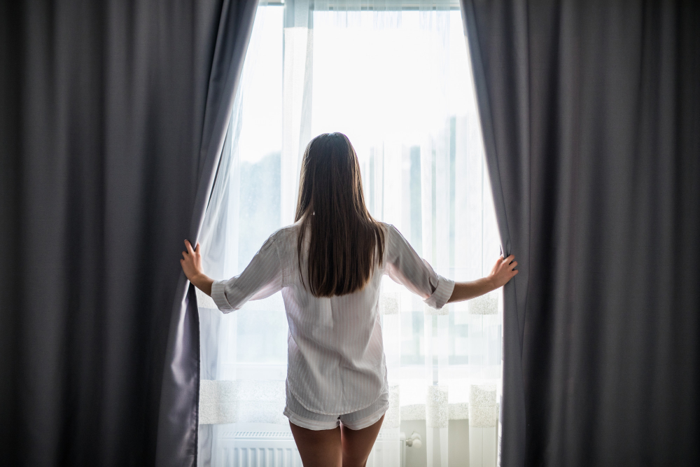 Beautiful Young Woman Opening Curtains Looking Through Window