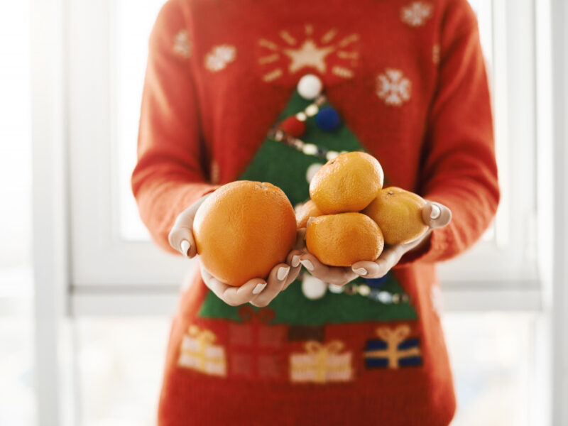 New Year Winter Concept Cropped Shot Female Funny Christmas Sweater Holding Orange Tangerines Offering It Friend Standing Near Window Girl Got Ill Boyfriend Brought Vitamin C