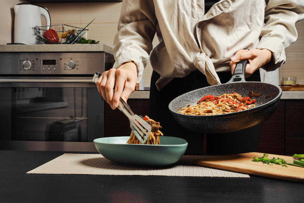 Unrecognizable Woman Moving Cooked Noodles With Vegetables Beef From Frying Pan Into Plate