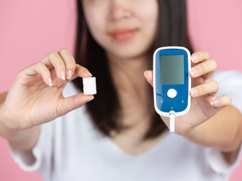 world-diabetes-day-woman-holding-glucose-meter-sugar-cubes-pink-wall