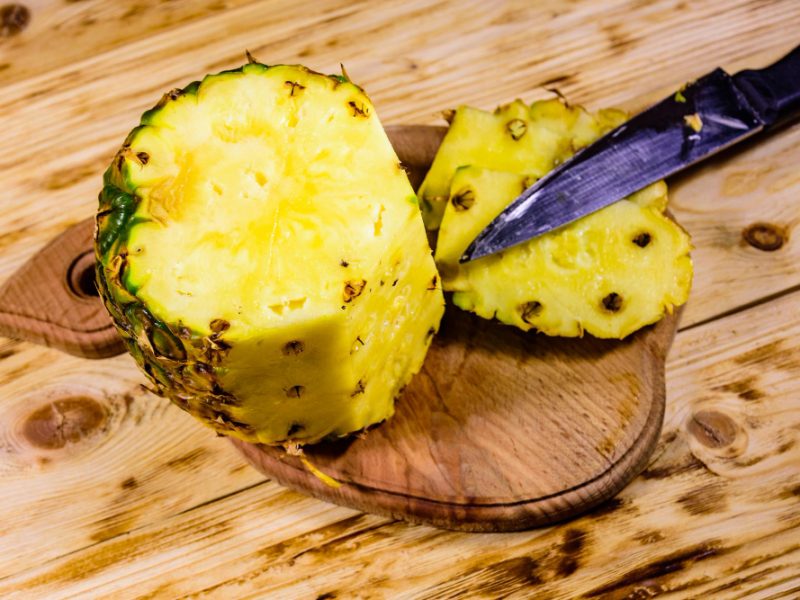 cutting-board-with-halved-pineapple-rustic-wooden-table