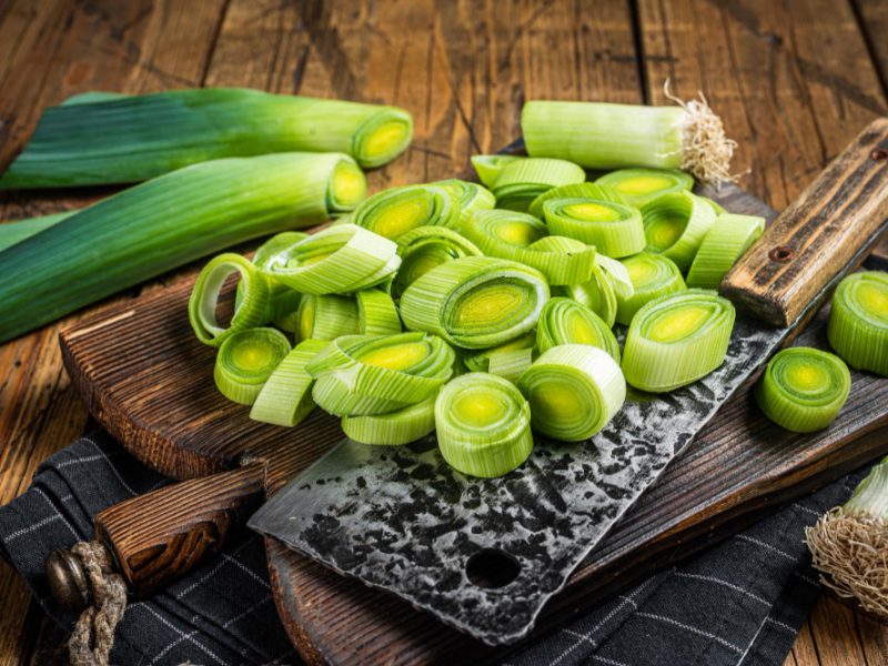 Chopped Green Leek Onion With Big Cleaver Cutting Board Wooden Background Top View