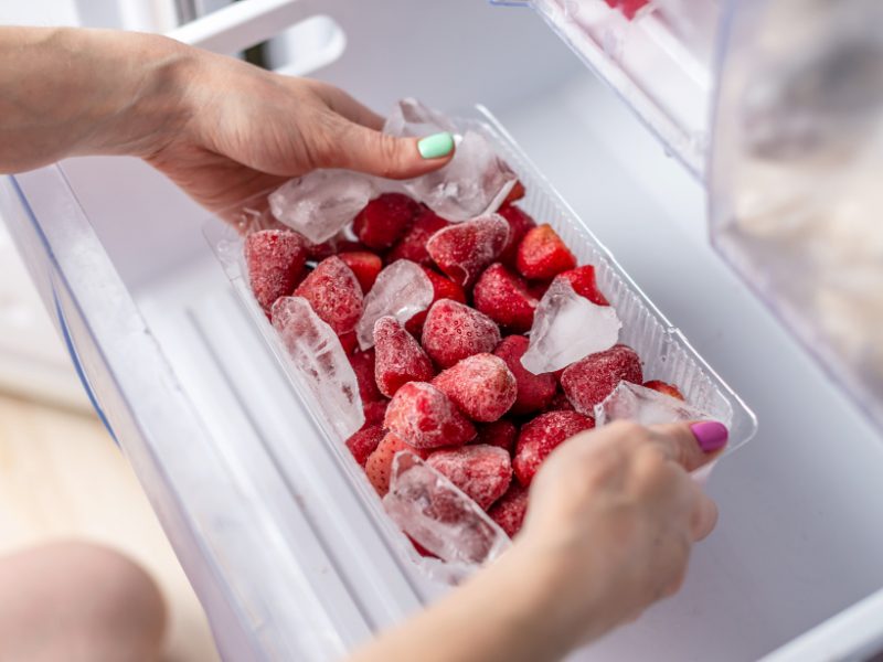 Woman S Hand Holding Container With Frozen Strawberries
