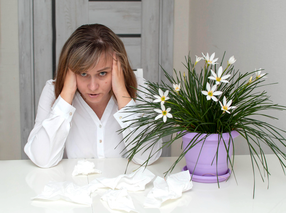 young-woman-with-allergies-holding-her-head-flowers-foreground-girl-suffering-from-allergies