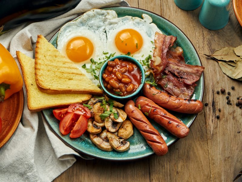 Classic English Breakfast Toasts Smoked Sausages Bacon Fried Eggs Beans Fried Toasts Blue Plate Top View Horizontal Wooden Surface
