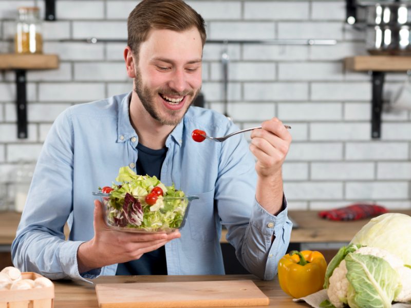 portrait-happy-man-eating-fresh-salad-kitchen